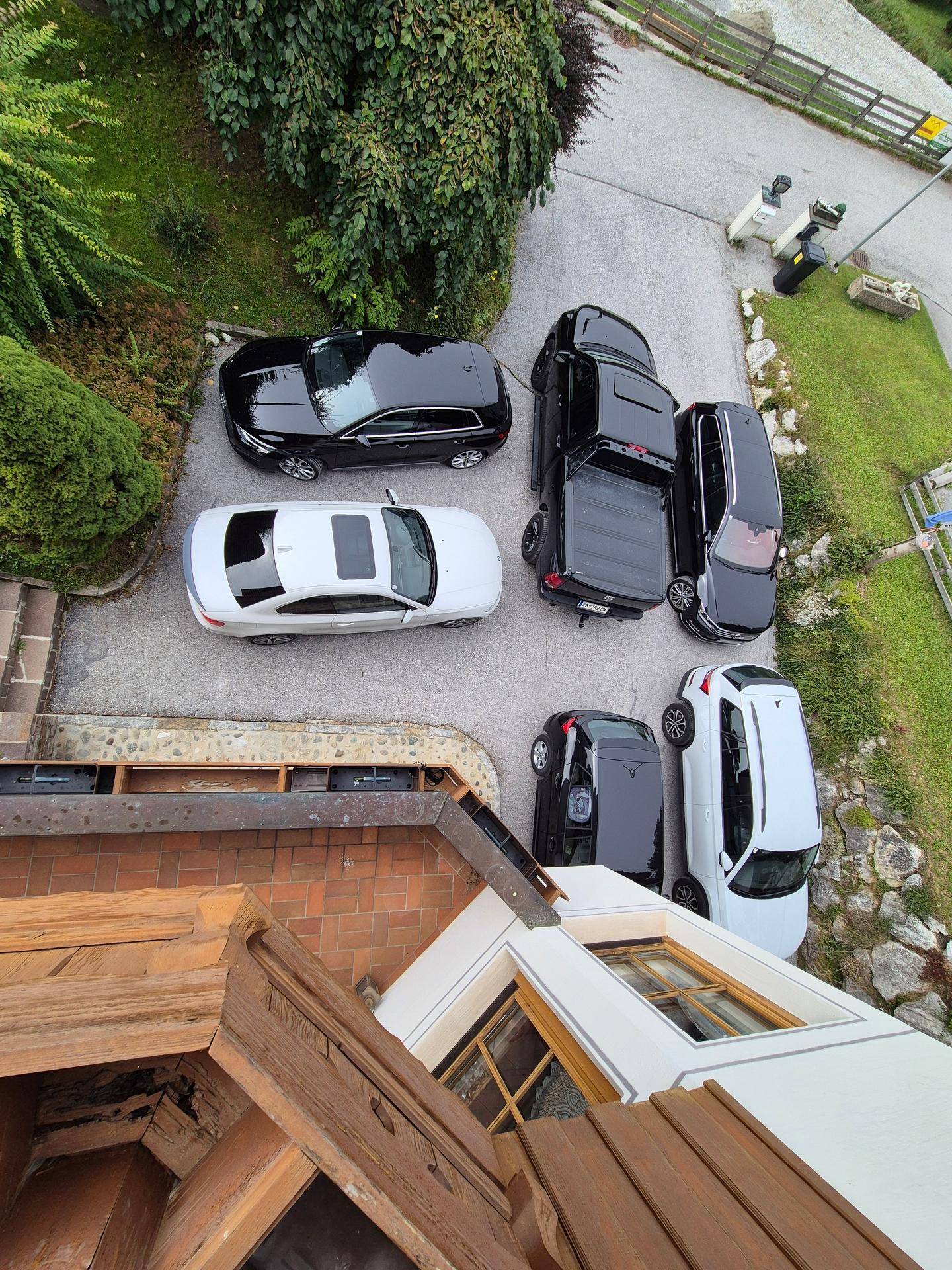 Blick von oben auf einen Parkplatz mit mehreren Autos und einem Teil des Daches.