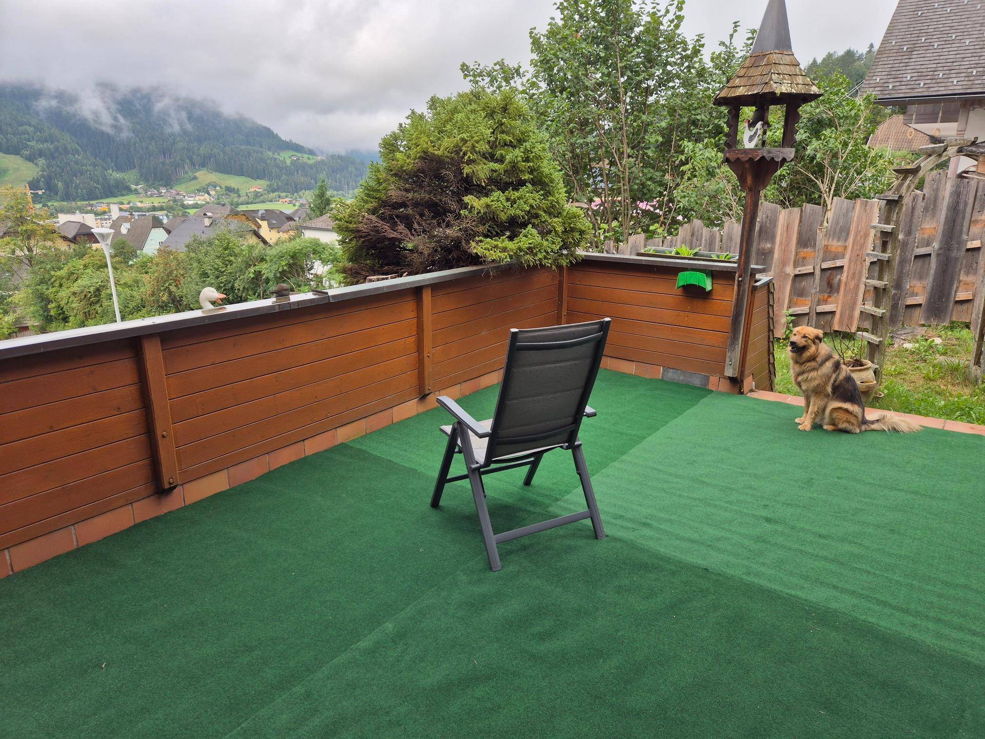 Geräumige Terrasse mit Kunstrasen und weitem Blick auf die umliegende Berglandschaft.