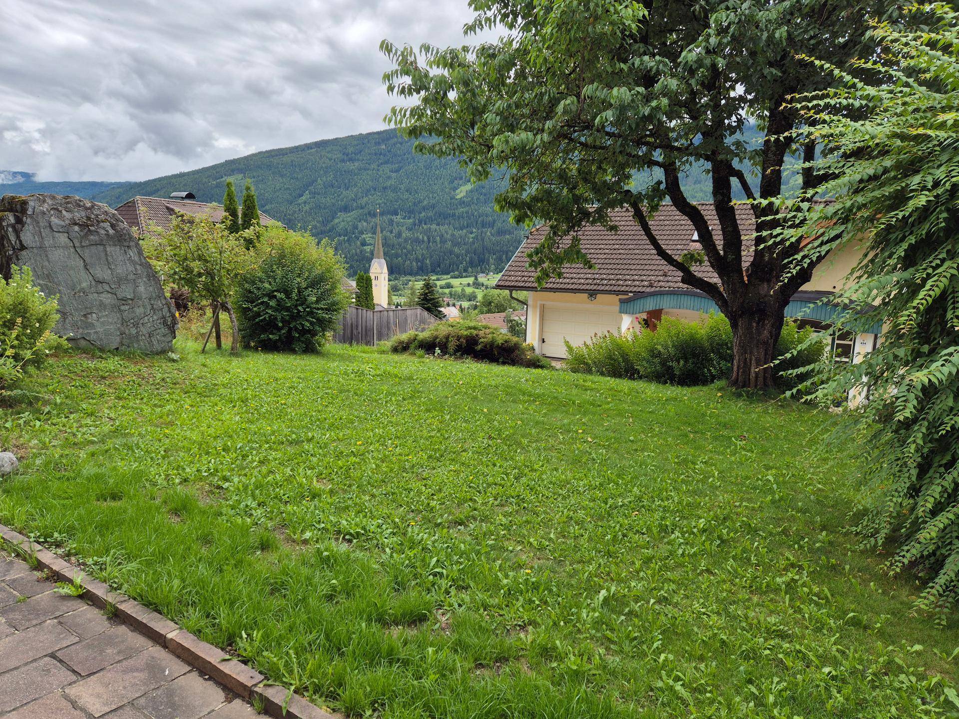 Weitläufiger Garten mit Rasenfläche und Blick auf eine Kirche im Tal.