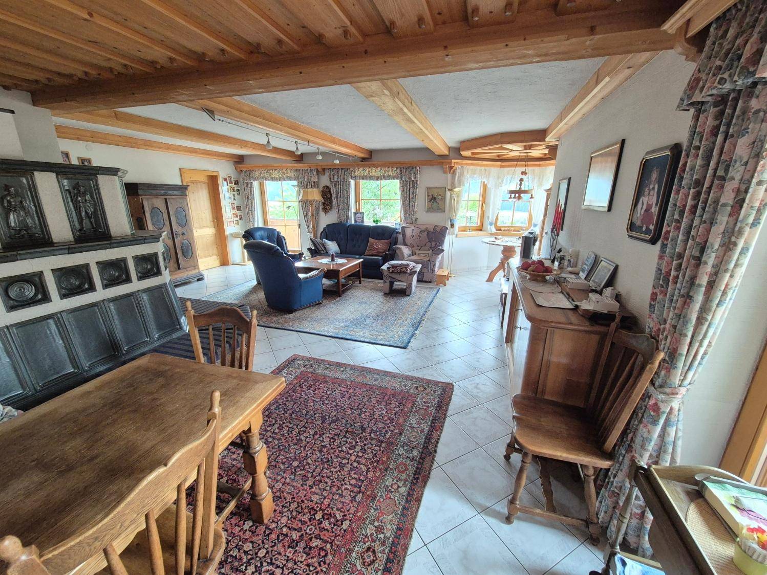 Geräumiger Wohnbereich mit Holzbalkendecke, Fliesenboden und traditionellen Möbeln, offen gestaltet.
