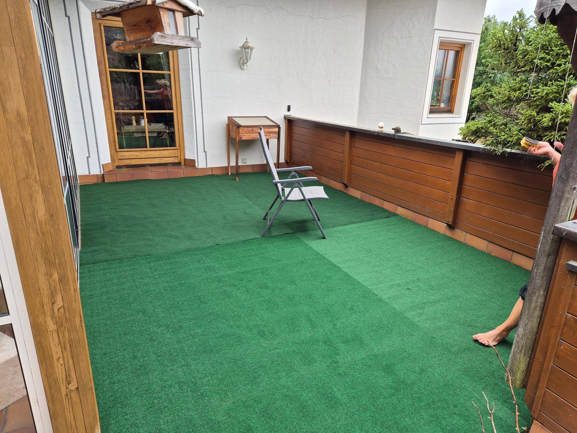 Große Terrasse mit Kunstrasen und Holzzaun, ideal für entspannte Stunden im Freien.