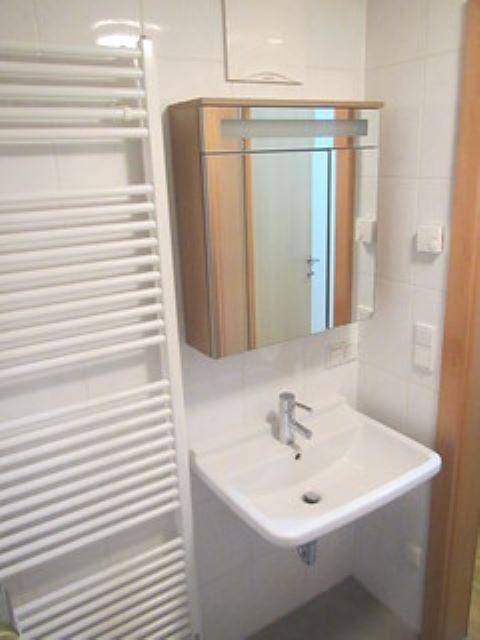 Modernes Badezimmer mit Waschbecken, Spiegelschrank und beheiztem Handtuchhalter.
