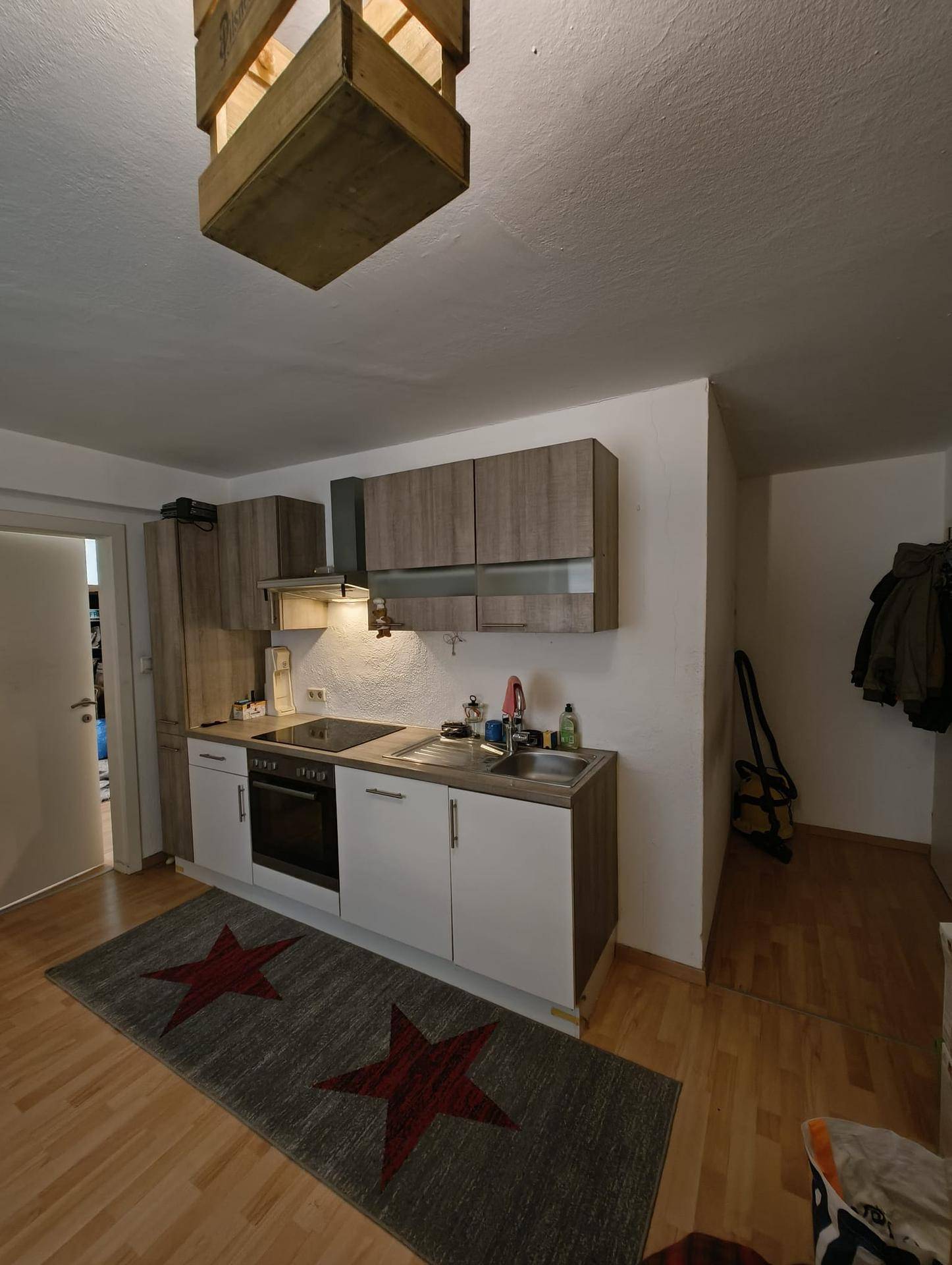 Funktionale Küchenzeile mit Holz- und weißen Schränken, integrierten Geräten und Holzboden.