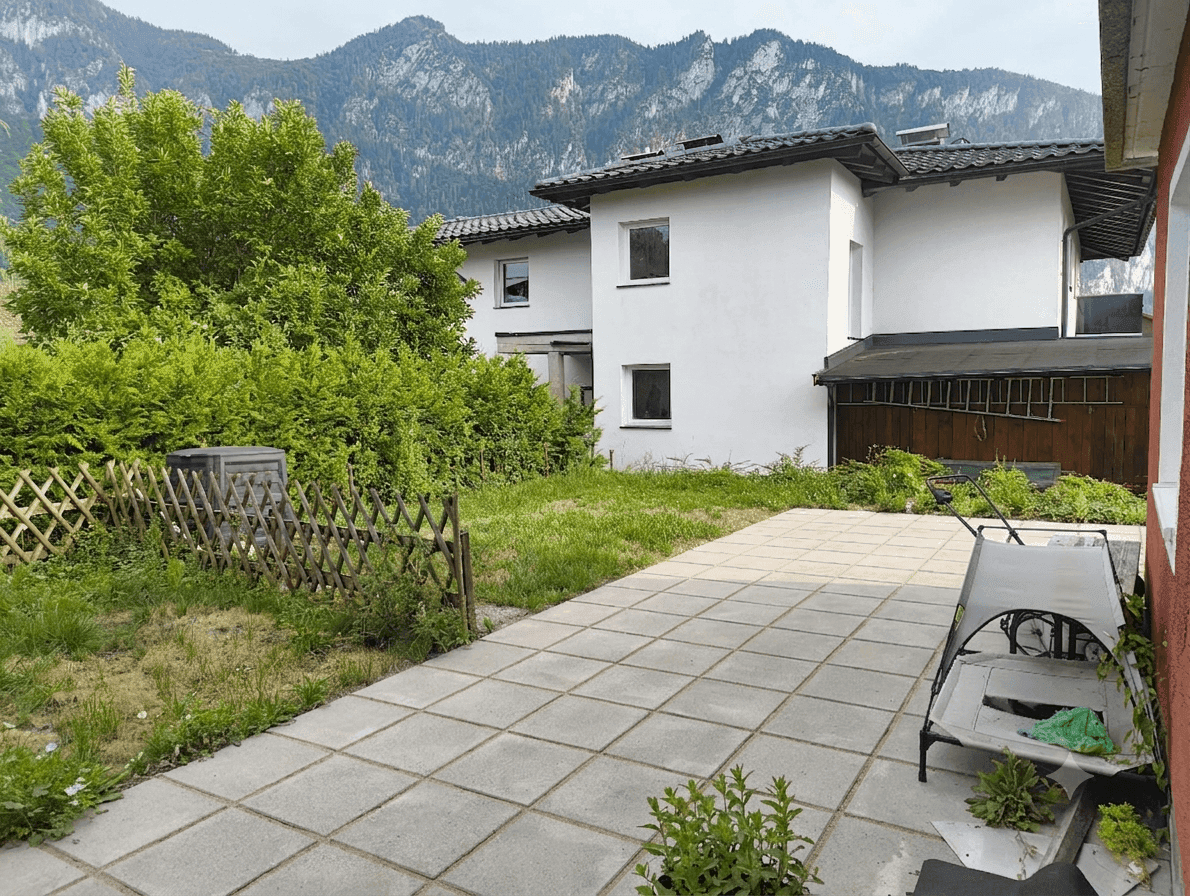 Gepflegte Terrasse mit Blick auf die Berge und einen grünen Gartenbereich.