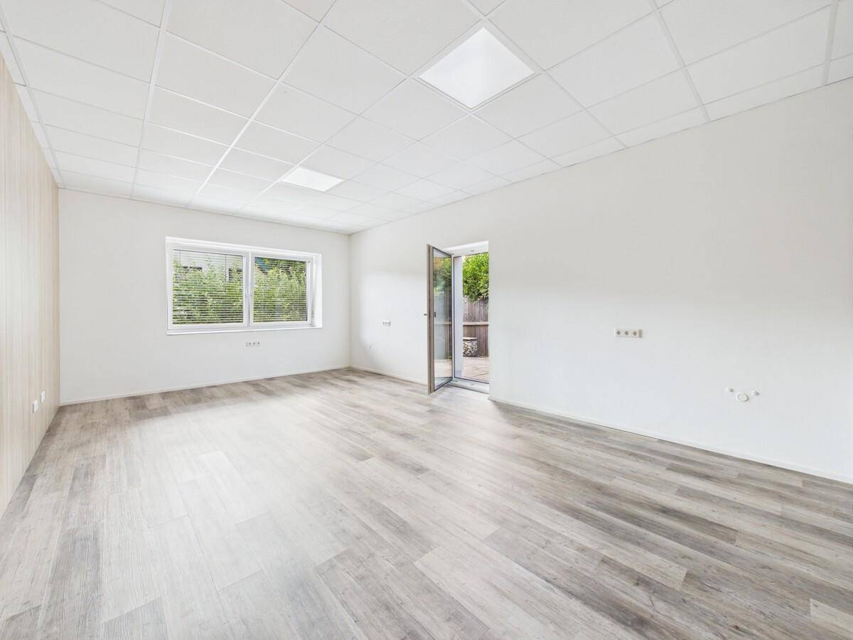 Geräumiges Büro mit Laminatboden und Zugang zu einem Außenbereich.