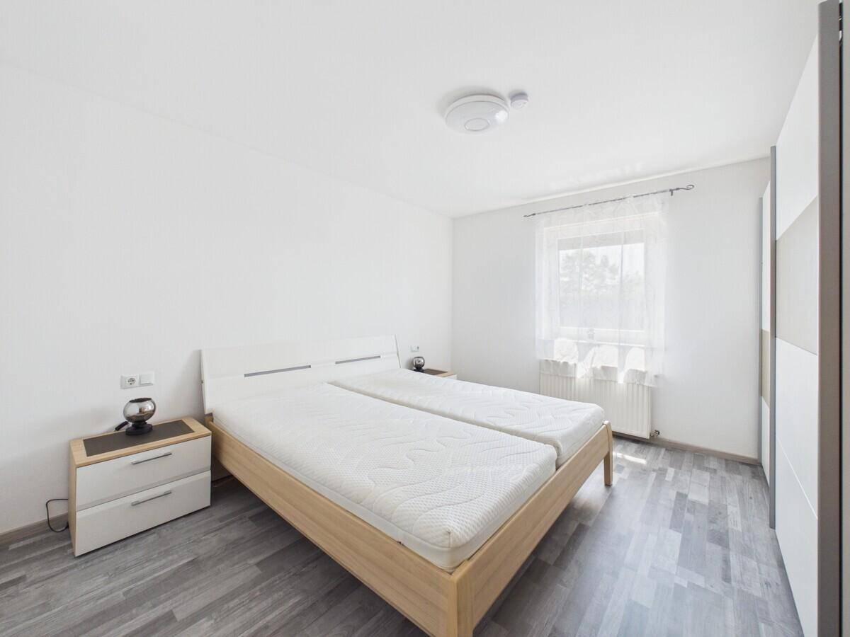 Helles Schlafzimmer mit Doppelbett, Nachttisch und Kleiderschrank, ausgestattet mit Laminatboden.