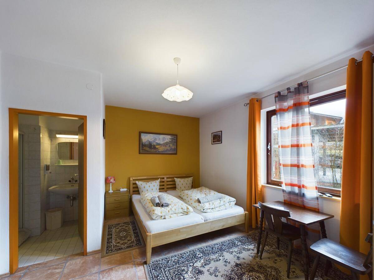 Schlafzimmer mit Doppelbett, angrenzendem Badezimmer und Fenster mit Blick ins Grüne.