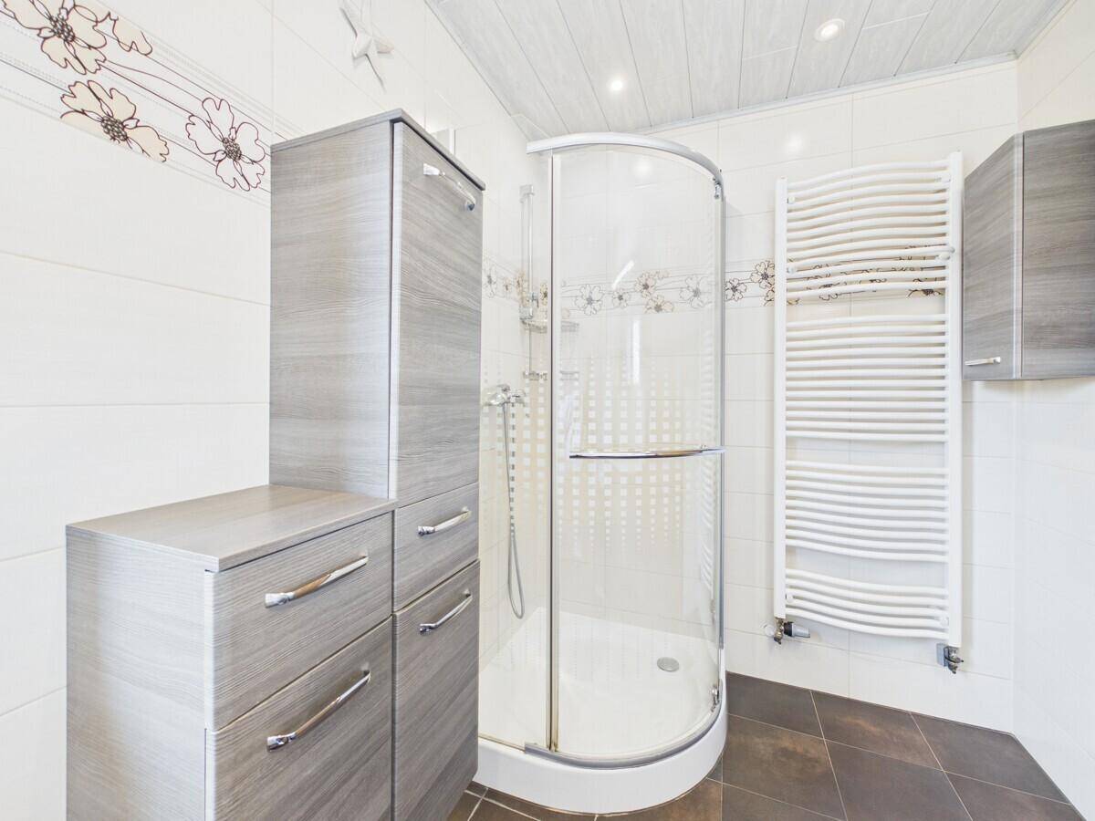 Modernes Badezimmer mit Duschkabine, beheiztem Handtuchhalter und praktischen Schränken.