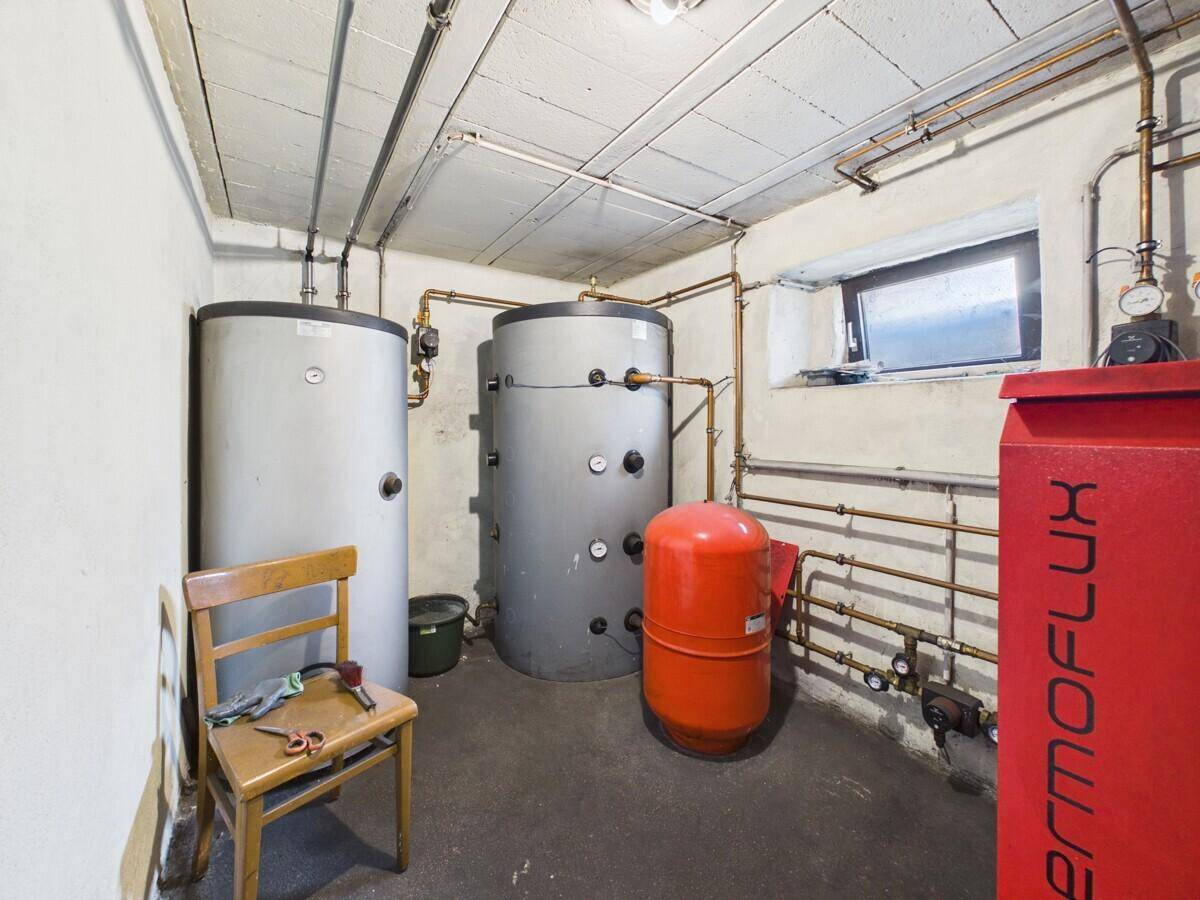 Heizungsraum im Keller mit zwei großen Wassertanks und sichtbaren Rohrleitungen.
