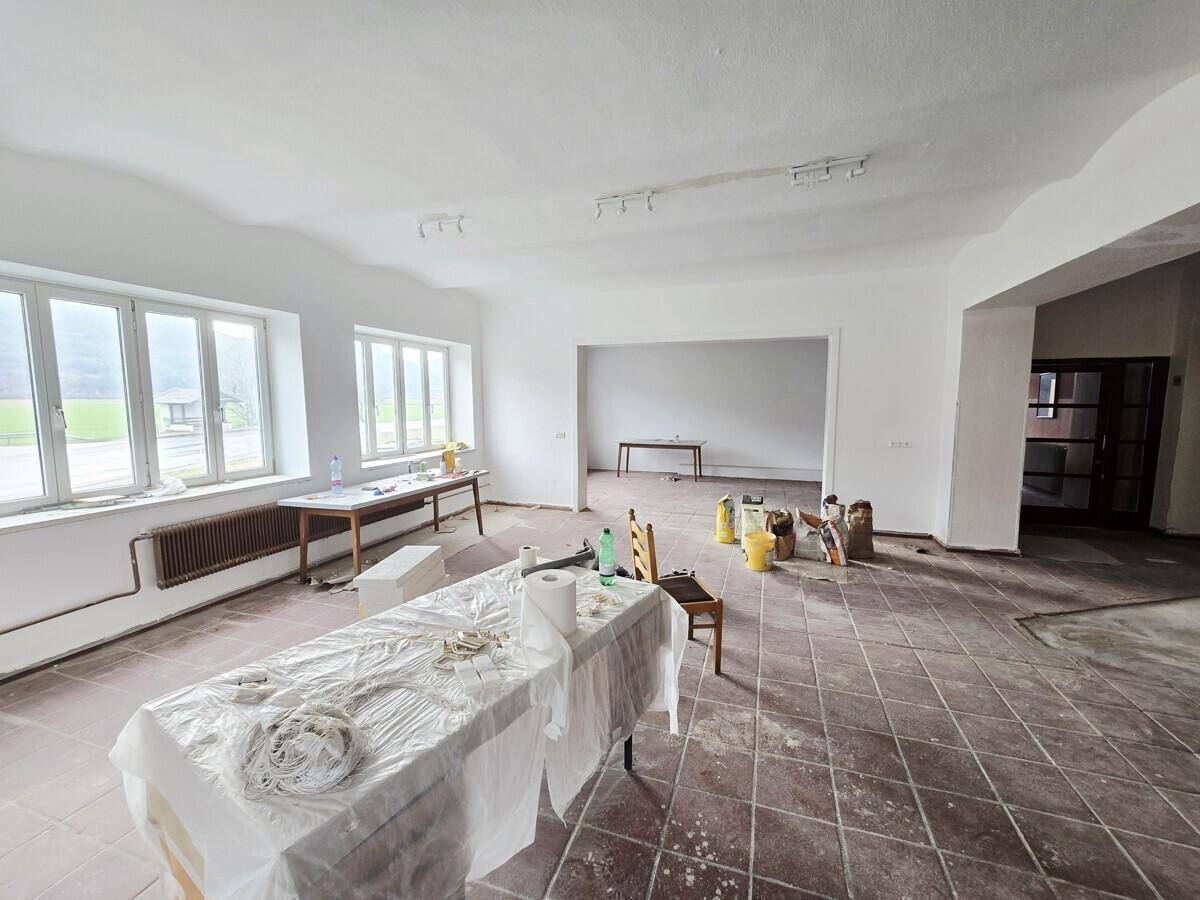 Großer, offener Raum mit Fliesenboden und Renovierungsbedarf, der viel Tageslicht durch die Fenster erhält.