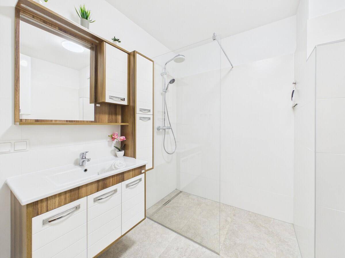 Modernes Badezimmer mit begehbarer Dusche, Waschtisch und Spiegelschrank.