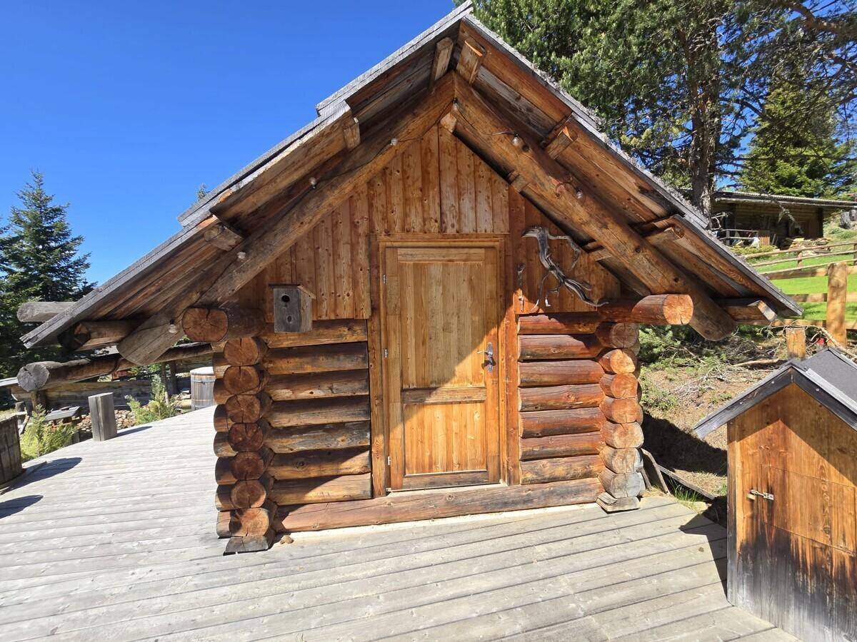 Freistehendes Holzgebäude im Blockhausstil mit Schindeldach und Holzterrasse.