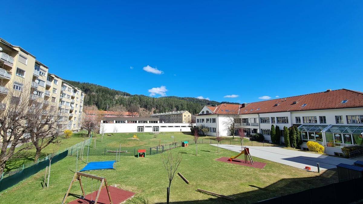 Großer Gemeinschaftsgarten mit Spielplatz und Blick auf die umliegenden Hügel.