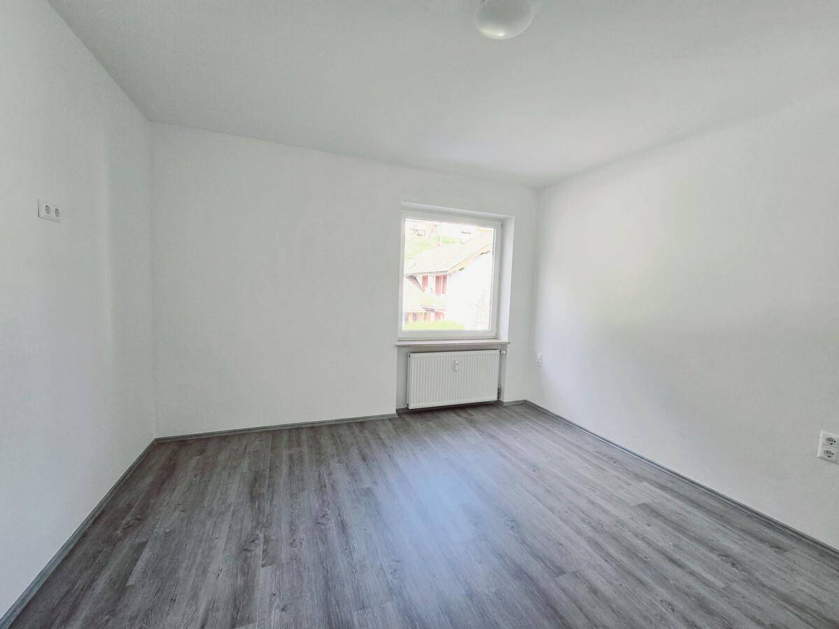 Freundliches Zimmer mit Laminatboden und weiß gestrichenen Wänden, ideal als Schlaf- oder Arbeitszimmer.