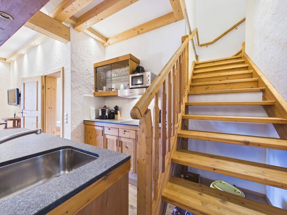 Holztreppe führt in die obere Etage, angrenzend an die offene Küche.