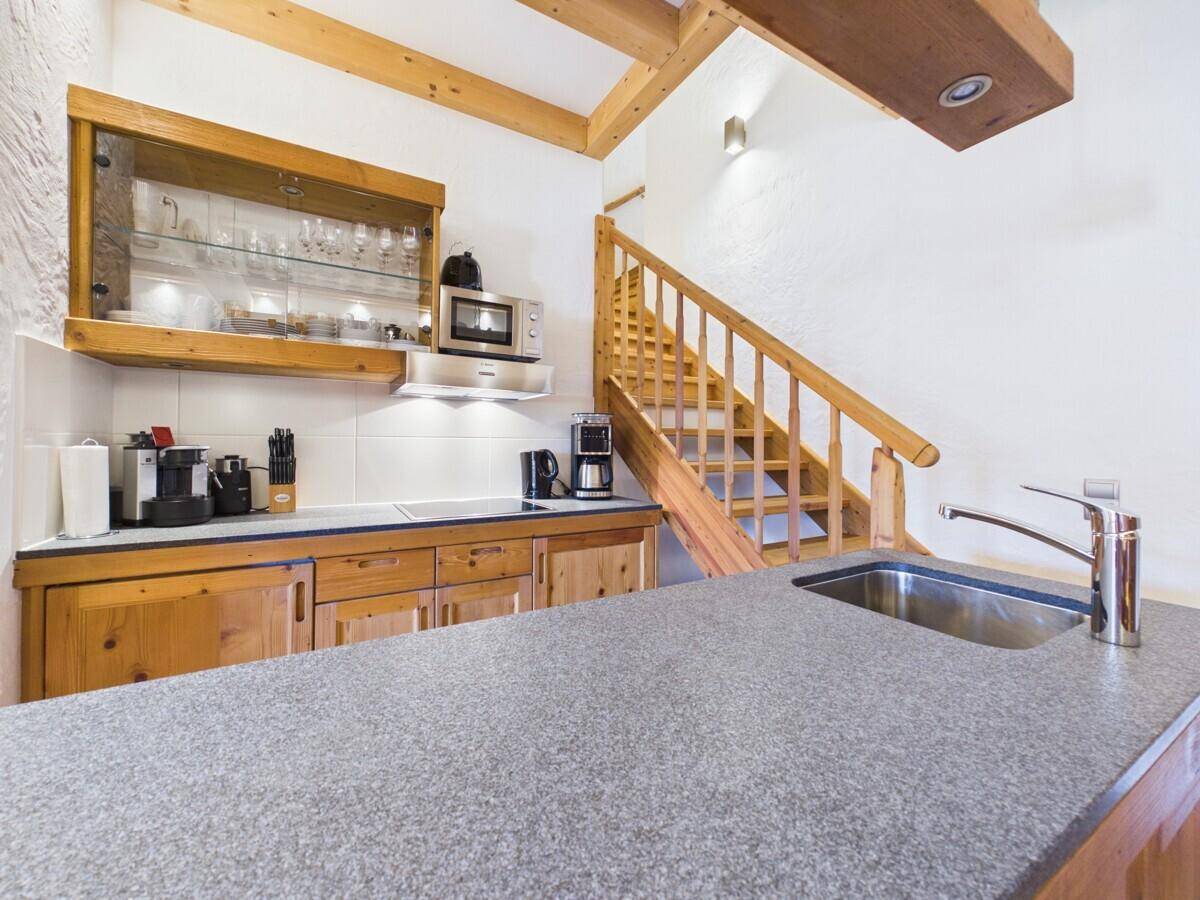 Funktionale Küche mit Holzschränken, Granitarbeitsplatte und integrierten Geräten.