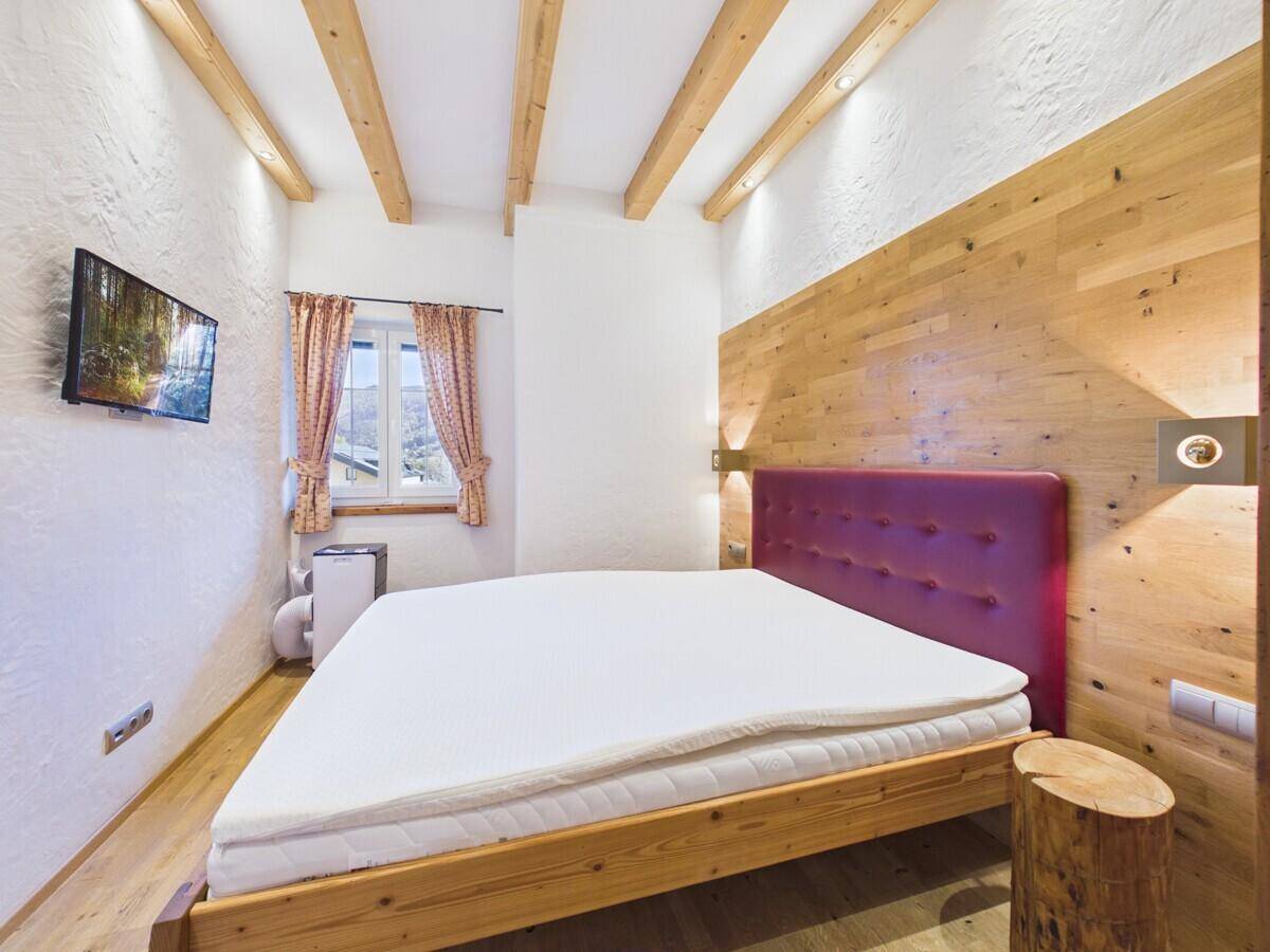 Schlafzimmer mit Holzboden, Holzwand und Blick auf die umliegende Landschaft.