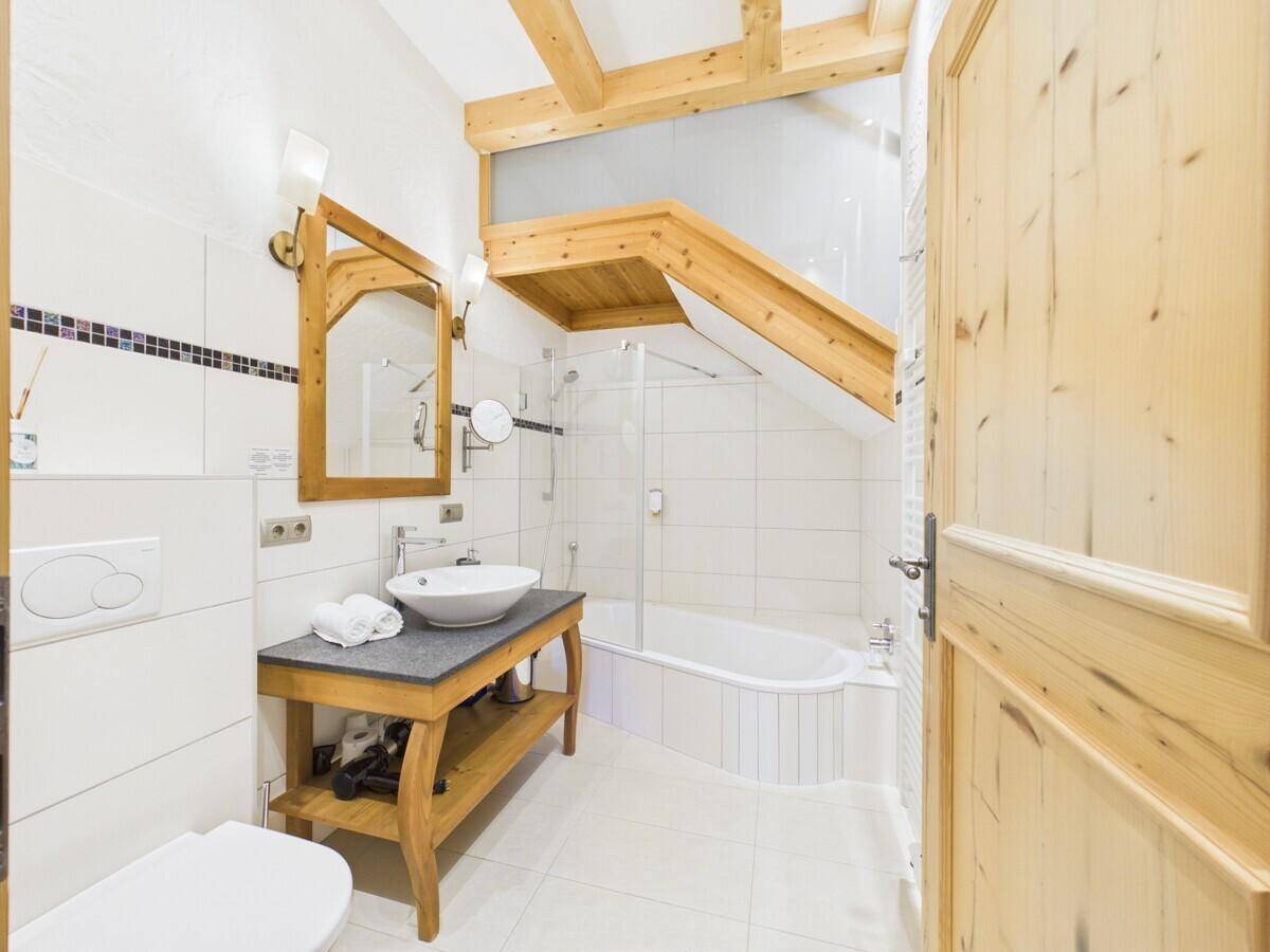 Stilvolles Badezimmer mit Holzwaschtisch, Badewanne und modernen Armaturen.