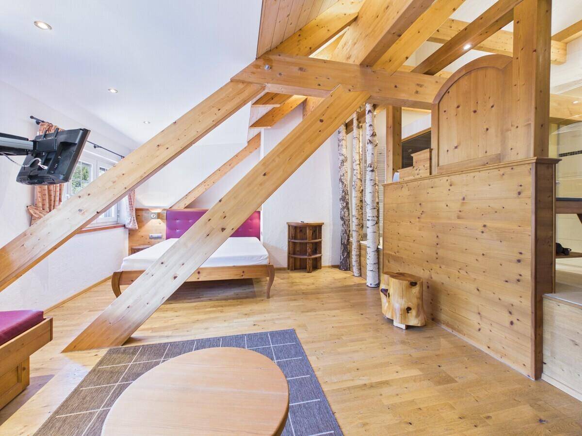 Geräumiges Schlafzimmer im Dachgeschoss mit Holzbalken, Sitzecke und rustikalem Charme.