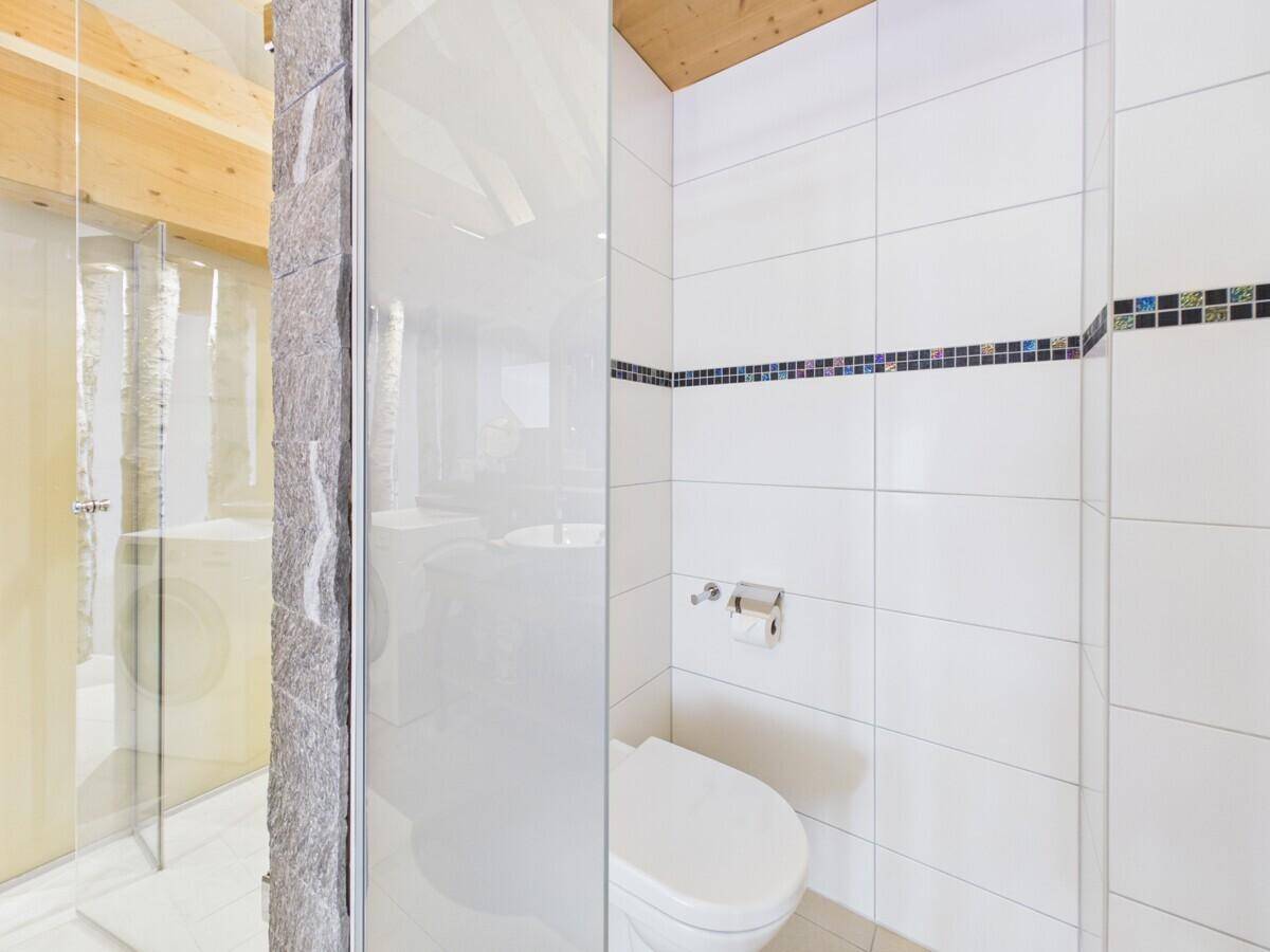 Separater Toilettenbereich mit weißen Fliesen und minimalistischem Design.