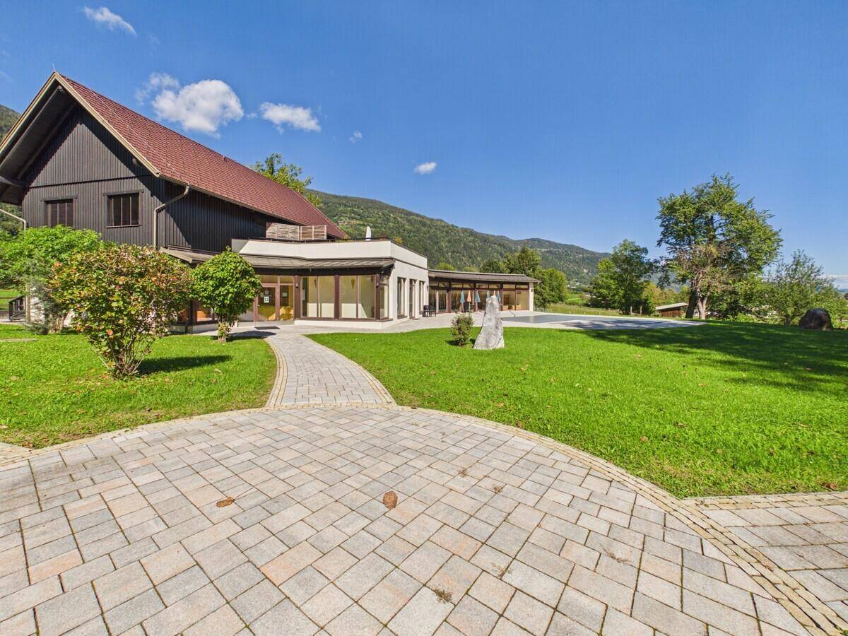 Weitläufige Grünfläche mit gepflastertem Weg und moderner Architektur im Hintergrund.