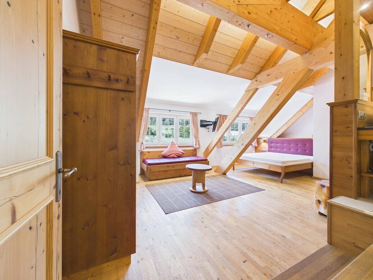 Geräumiges Schlafzimmer mit sichtbaren Holzbalken, Holzboden und rustikalen Möbeln.
