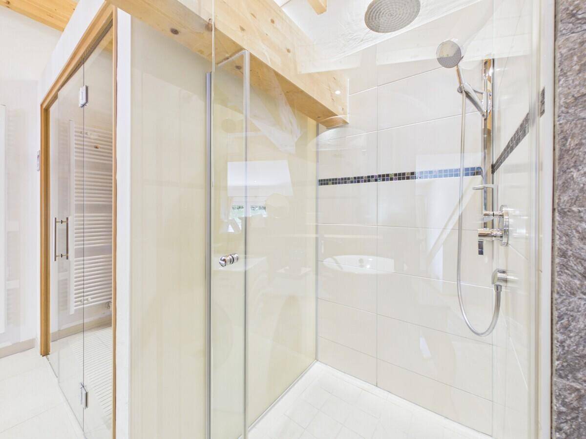 Geräumige Duschkabine mit Glaswänden, Regendusche und modernen Fliesen.