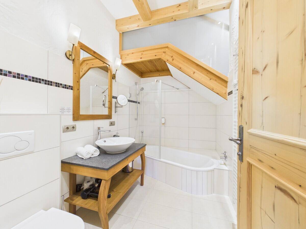 Modernes Badezimmer mit Waschtisch, Badewanne und weißen Fliesen unter Dachschräge.