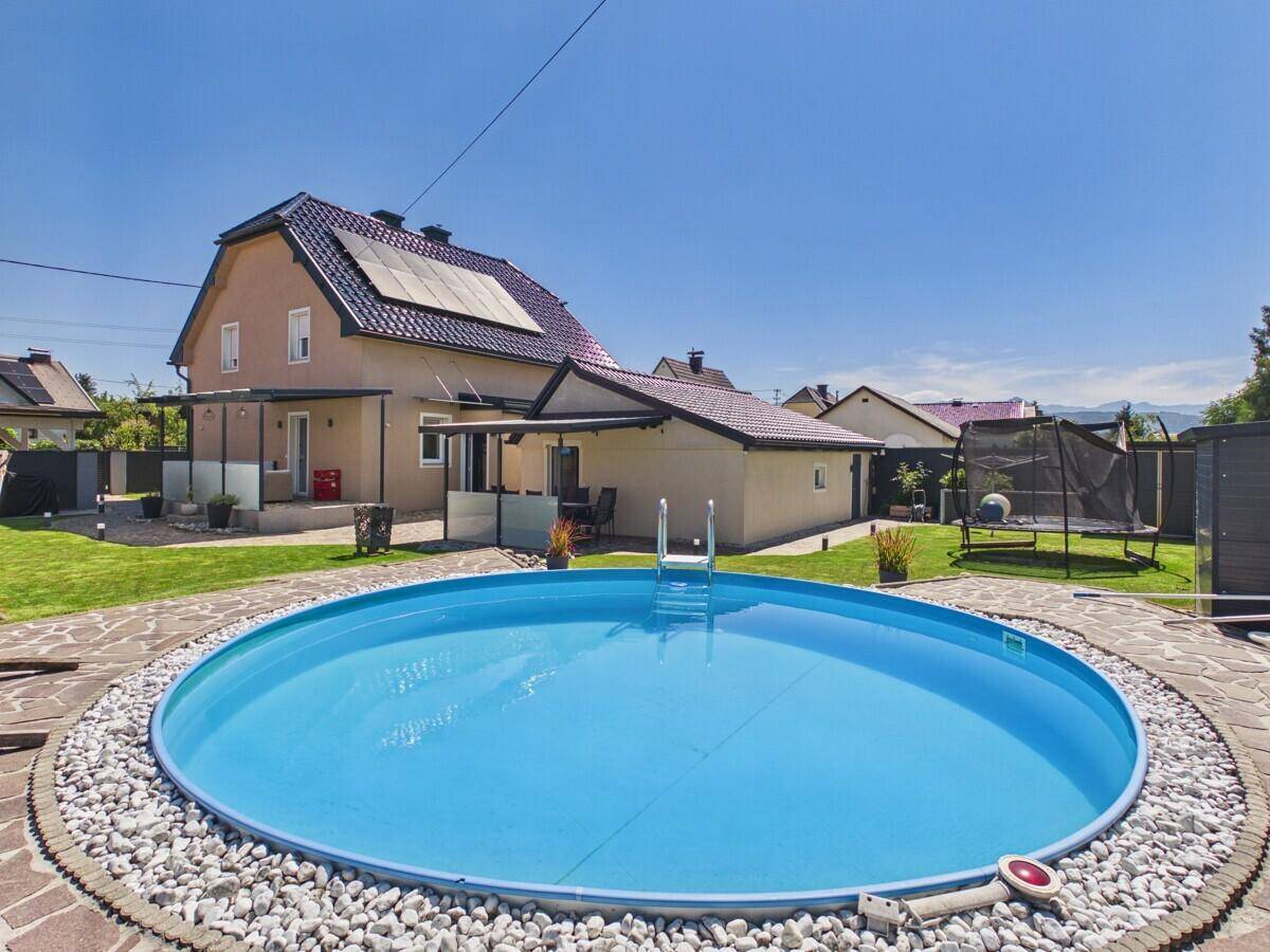 Großer Garten mit rundem Aufstellpool, Rasenfläche und Trampolin hinter dem Haus.