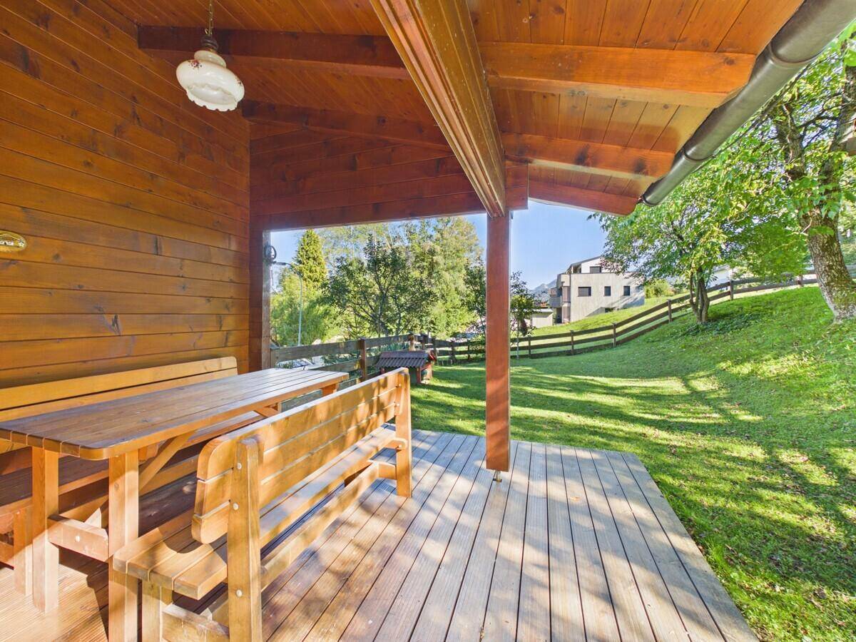 Überdachte Holzterrasse mit rustikalen Sitzgelegenheiten und Blick auf die grüne Umgebung.