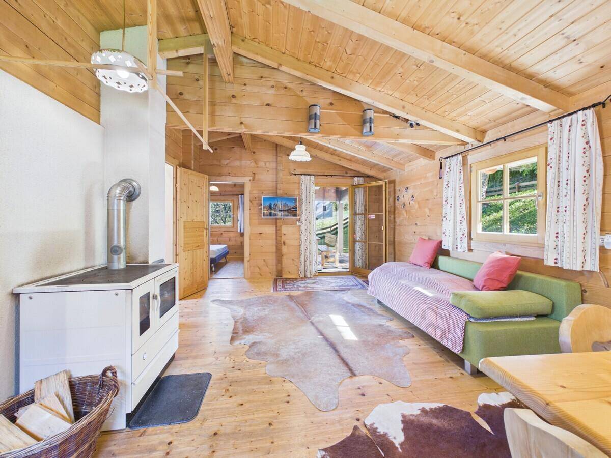 Gemütliches Wohnzimmer mit Sofa, Holzofen und Zugang zur Terrasse oder Balkon.