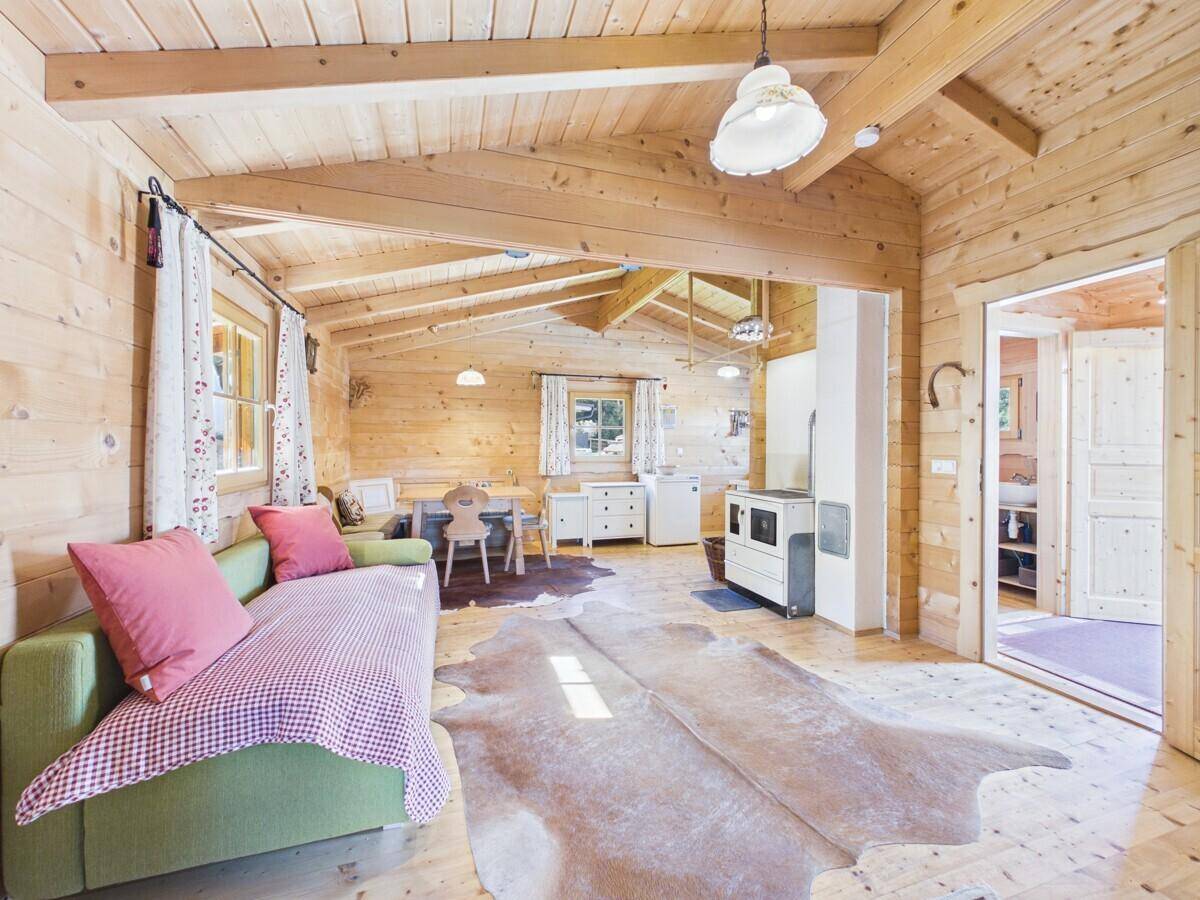 Gemütlicher Wohn-Essbereich in einem Holzhaus mit Holzbalkendecke und traditionellem Ofen.