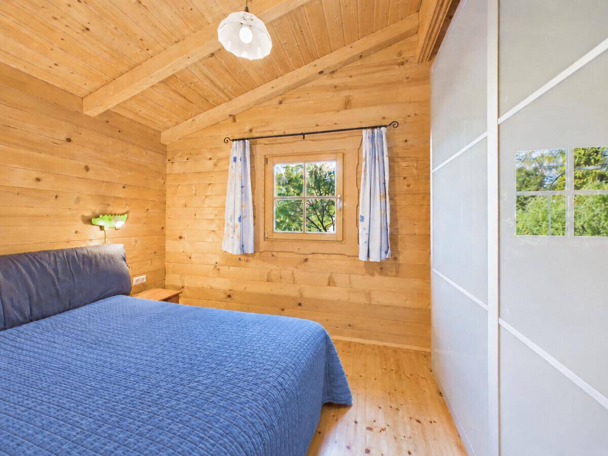 Schlafzimmer mit Holzwänden, Dachschräge, Doppelbett und Blick ins Grüne.