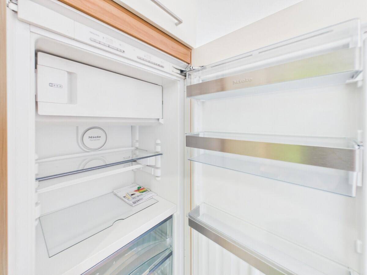 Offener Kühlschrank der Marke Miele mit leeren Glasablagen, bereit zur Nutzung.