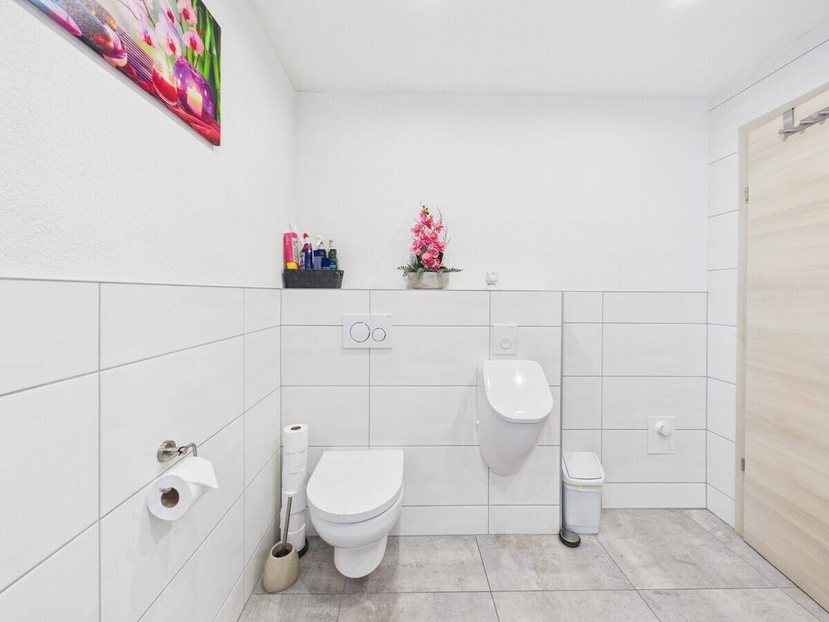 Separates WC mit modernem Urinal, Wand-WC und weißen Fliesen.