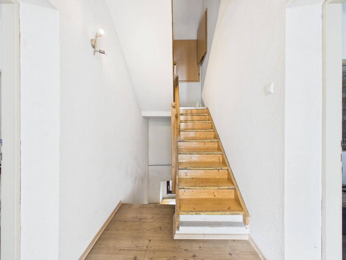 Heller Flur mit Holztreppe, die in die oberen Stockwerke führt, und Laminatboden.