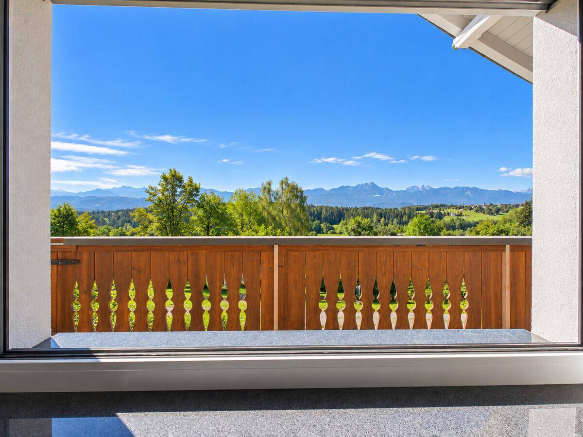 Atemberaubender Bergblick von einem sonnigen Balkon mit Holzbalkongeländer.