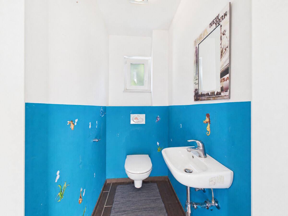 Kleines Gäste-WC mit blauen und weißen Wänden, Toilette und Waschbecken.