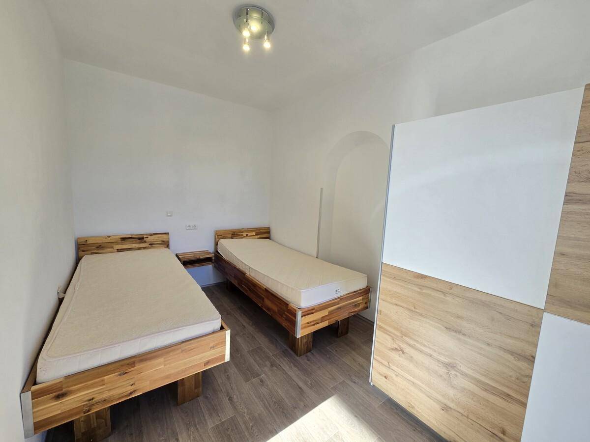 Schlafzimmer mit zwei Holzbetten, Holzboden und einem großen Dachfenster für viel Tageslicht.