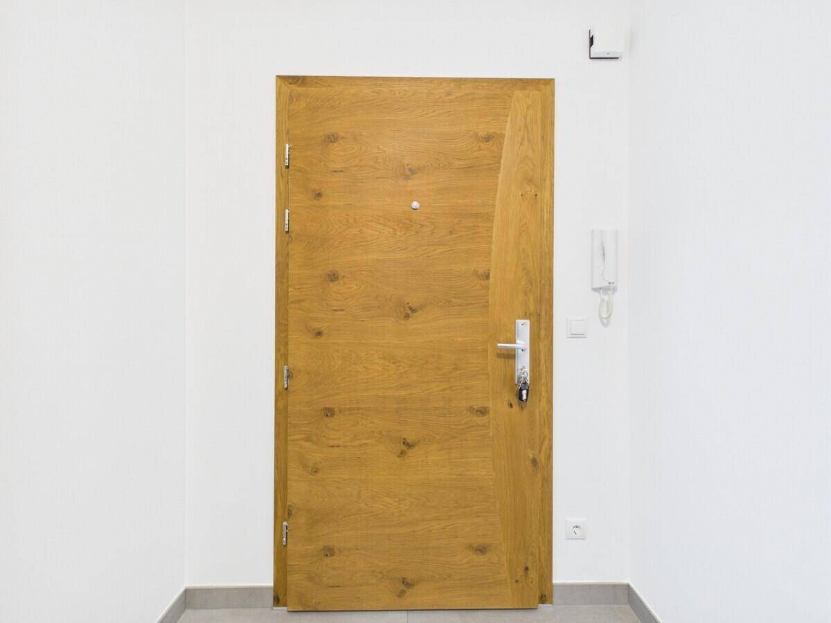Moderne Eingangstür aus Holz mit Spion und Gegensprechanlage.