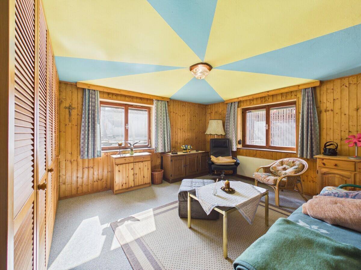 Farbenfrohes Schlafzimmer mit Holzvertäfelung, Teppichboden und einzigartiger Deckenbemalung.