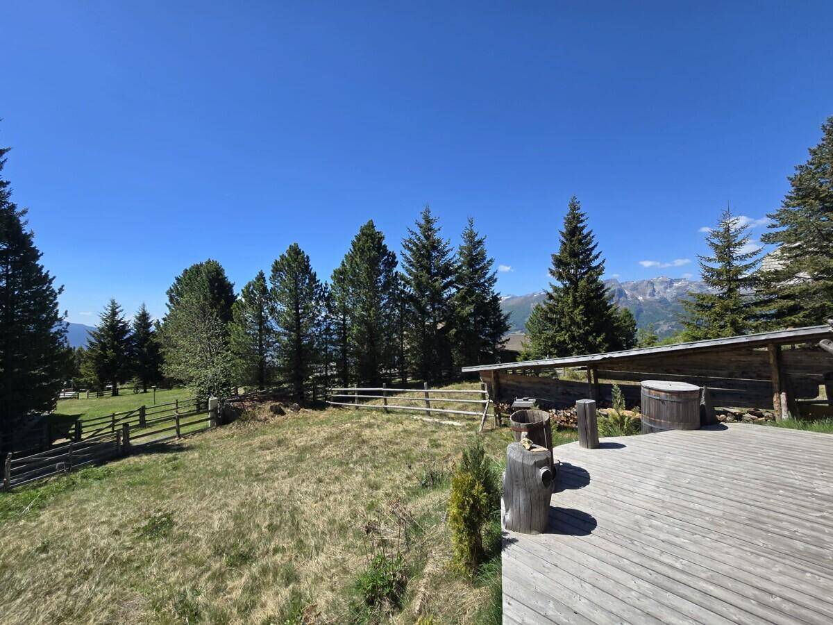 Weitläufige Holzterrasse mit Blick auf die grüne Landschaft und die fernen Berge.