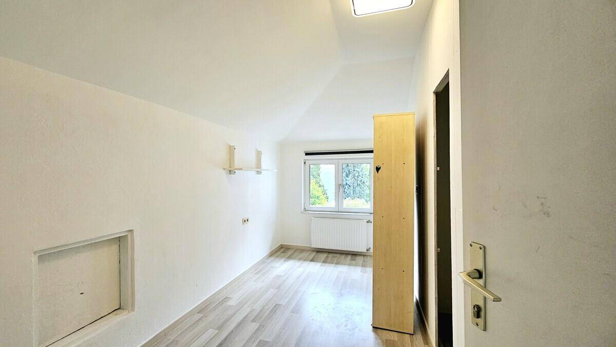 Geräumiges Schlafzimmer mit Dachschräge, Laminatboden und praktischer Nische.