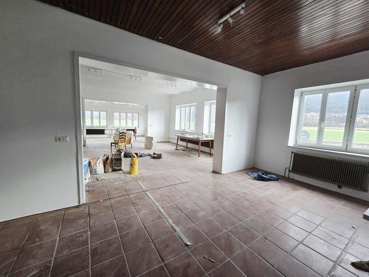 Großer, offener Raum mit Fliesenboden und Holzdecke, der auf eine Renovierung wartet und viel Tageslicht bietet.