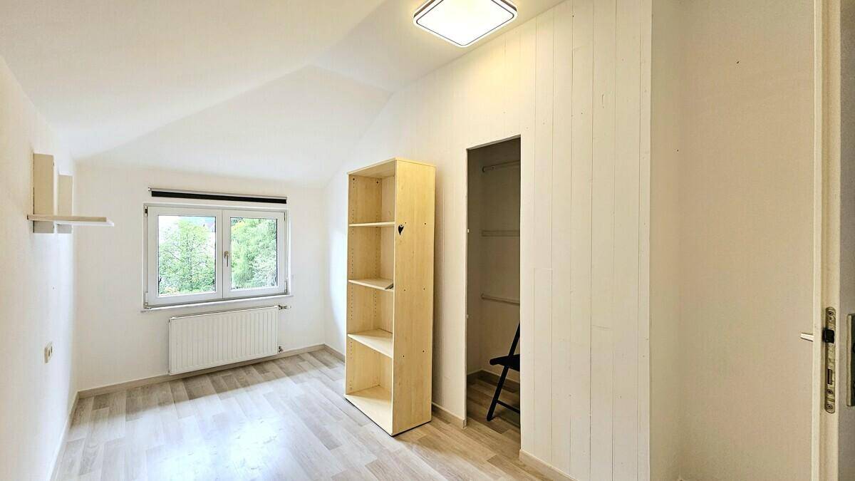 Helles Schlafzimmer mit Dachschräge, Laminatboden und integrierter Schranknische.