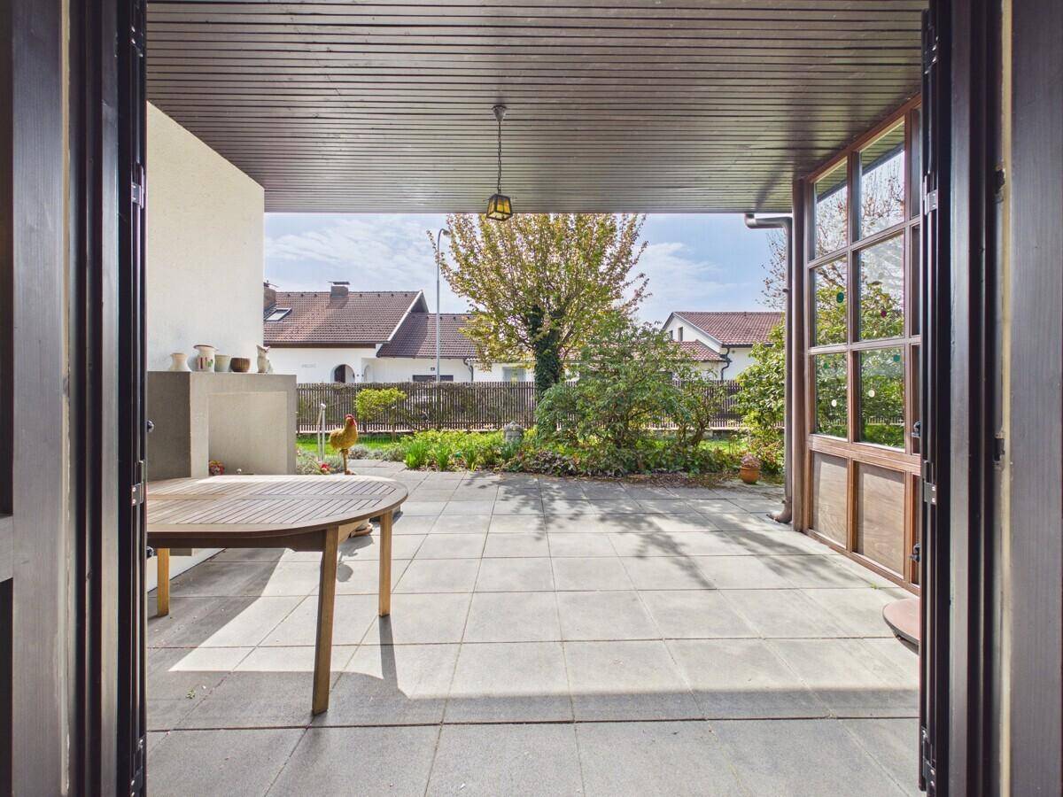 Geräumige überdachte Terrasse mit Blick auf den Garten und viel Tageslicht.