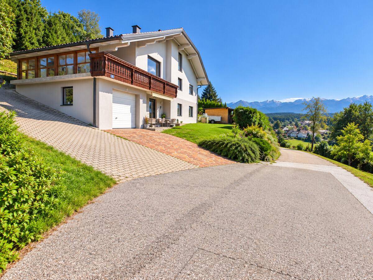 Hausfassade mit Garage, Auffahrt und weitem Blick auf die umliegende Landschaft und Berge.