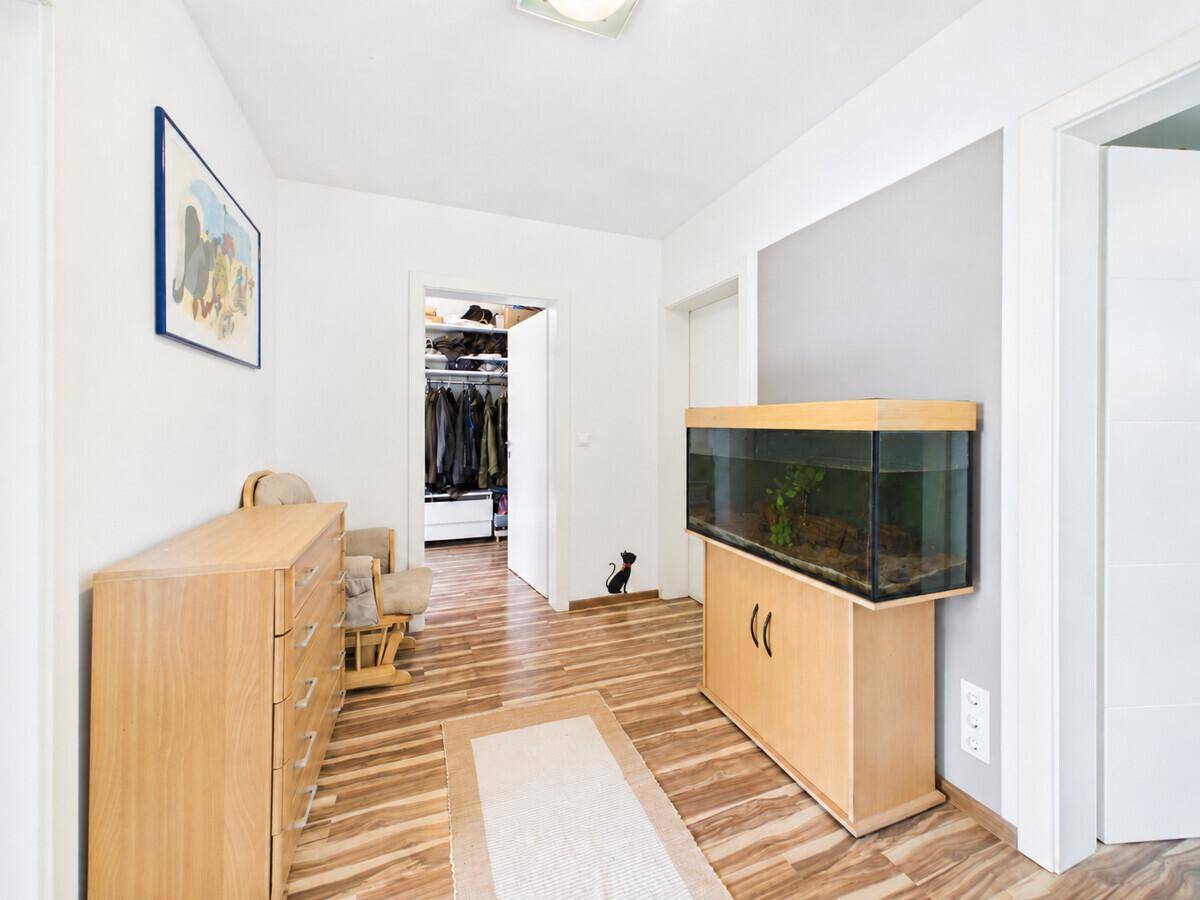 Heller Flur mit Holzmöbeln, Aquarium und Zugang zu einem begehbaren Kleiderschrank.
