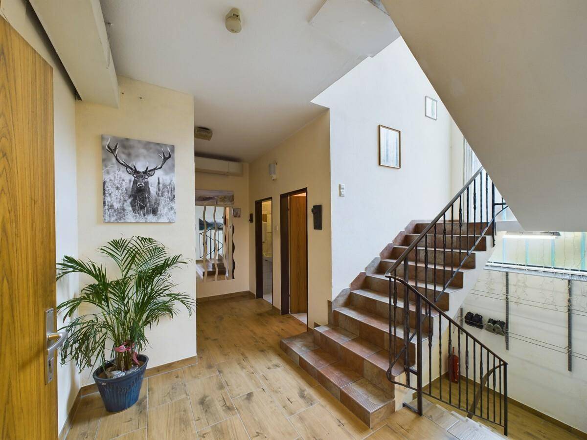 Heller Flur mit Holzoptik-Fliesenboden und Treppe zu den oberen Etagen.