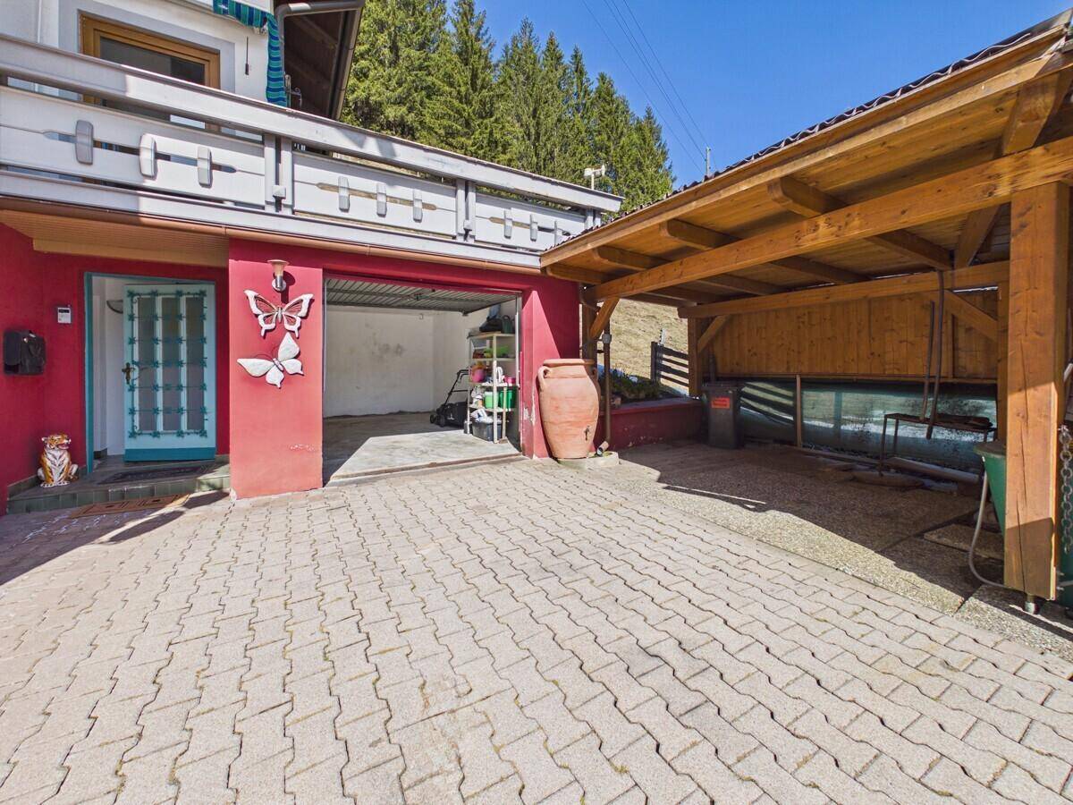 Geräumige Garage und überdachter Carport mit gepflasterter Zufahrt, ideal für Fahrzeuge.